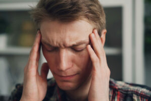 person rubbing their hands on their temples on their head